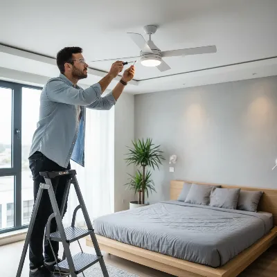 Person checking and maintaining a ceiling fan for longevity, illustrating wear and tear inspection and lubrication points