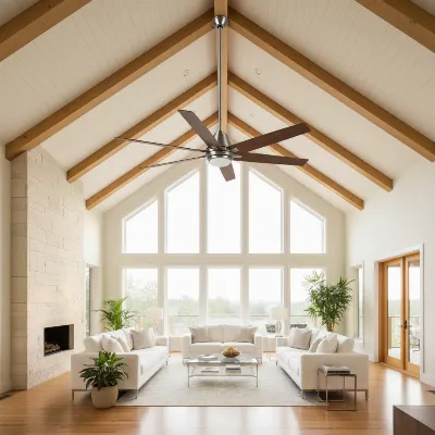 A modern large ceiling fan with sleek, long blades installed on a high vaulted ceiling in a spacious living room with natural light.